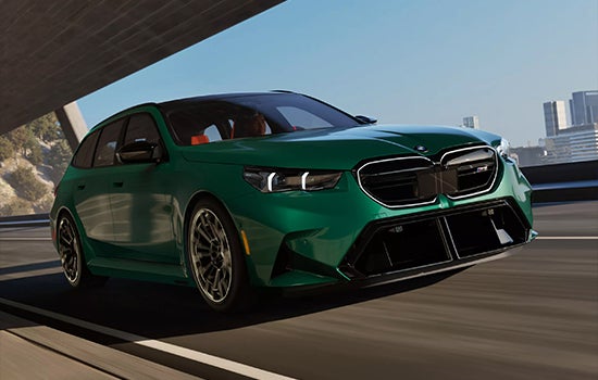 Green BMW M5 Touring driving on a city road. | Flemington BMW in Flemington NJ