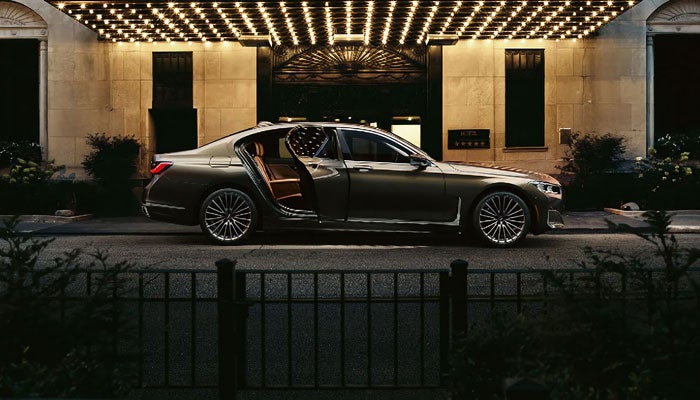 A BMW 7 Series Sedan parked outside a hotel at night.