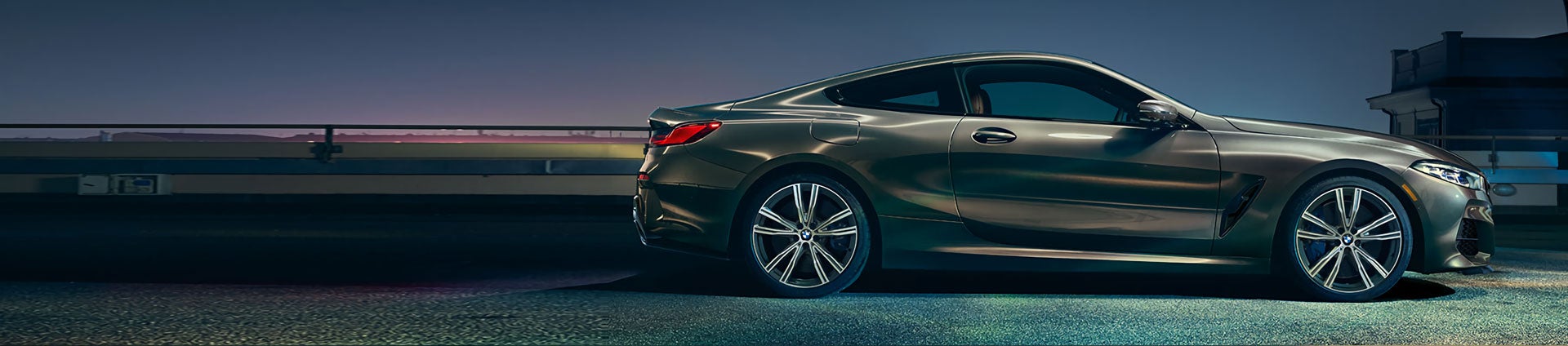 A grey metallic BMW 8 Series parked during dusk.